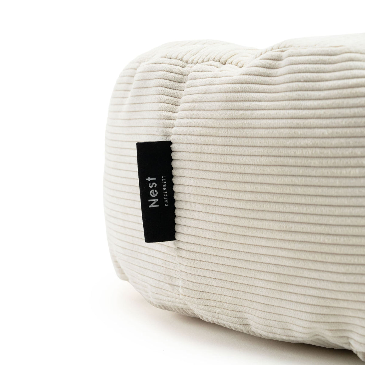 Nahaufnahme des weißen Cord-Katzenbetts mit schwarzem „Nest“-Label