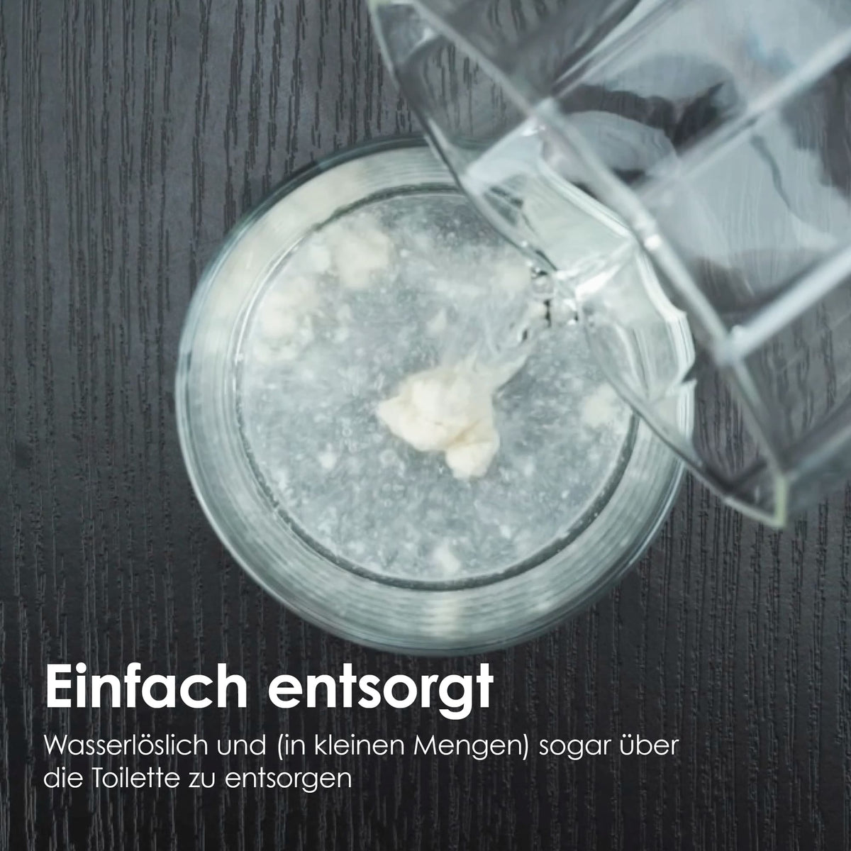 Nahaufnahme davon, wie das Katzenstreu in einem Glas Wasser aufgelöst wird, mit Text: "Einfach entsorgt"