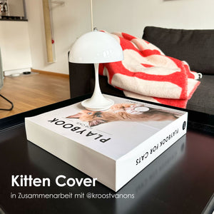 LucyBalu Playbook mit Kitten Cover als dekoratives Katzen Spielzeug im Coffee Table Book Design auf einem Wohnzimmertisch.